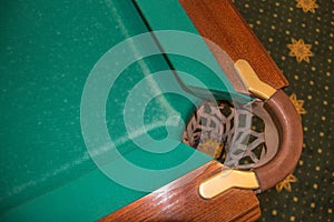 A close-up detail of a luxurious billiard table with a pocket for balls of their leather and metal, a copy of the space