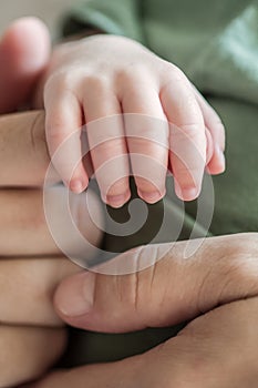 Close-up detail macro view of baby holding on to parent finger with his little hand