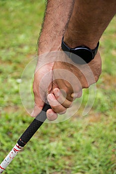 Close-up detail of man`s hands with black digital watch, holding golf club,