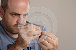 Close-up detail of man threading a sewing needle with thread. Selective focus on hands. Copy space