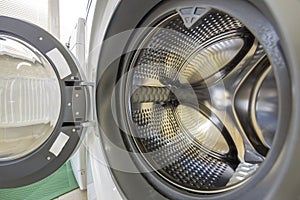 Close-up detail of modern washing machine interior with open door interior. Silver shiny stainless drum, design and technology