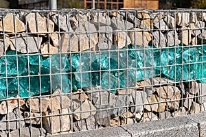 Close-up detail of new modern beautiful gabion fence with metal cage filled by crushed stone and shattered artificial