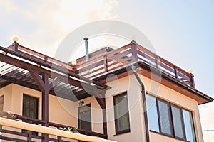 Close-up detail of new modern ecological cottage house top with shingled brown roof on blue sky background