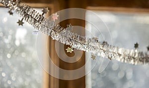 Close-up detail new year Christmas decoration, silver stars and rain on window light blurred bokeh background. Sparkling DIY