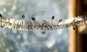 Close-up detail new year Christmas decoration, silver stars and rain on window light blurred bokeh background. Sparkling DIY