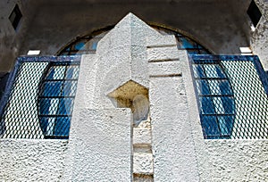 Close-up of detail of old grungy art deco building with round window about stucco entryway