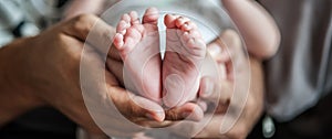 Close-up detail of parent holding cute and soft baby small leg in his hands