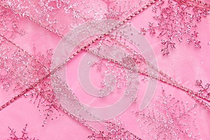 Abstract textured background of pink net ribbon with glitter snowflakes