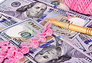 Close up detail of pink crochet lace and crochet needle sitting on top of US dollas