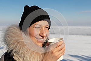 Close-up detail portrait of young adult beautiful woman wear warm jacket and knitted hat hold paper cup enjoy drink hot