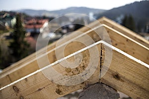 Close-up detail of roof frame of rough wooden lumber beams on background of misty mountain landscape in ecological area. Building