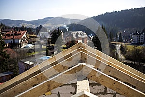 Close-up detail of roof frame of rough wooden lumber beams on background of misty mountain landscape in ecological area. Building