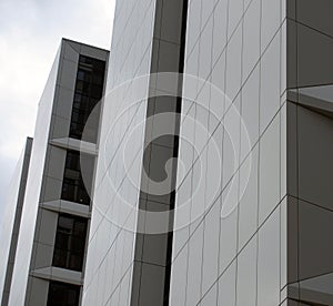 detail of a row of tall high rise modern apartment buildings with white cladding and dark windows