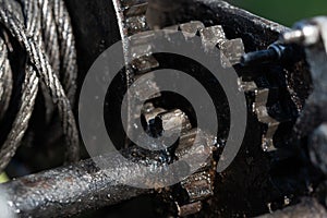Close-up and detail shot of a greased winch. You can see the gears, the pulley and the steel cable