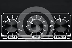 Close up detail of sound equalizer control knobs of a black guitar amplifier