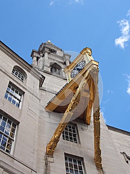 A close up detail of the tower and large ornate gold clock on leeds civic hall in west yorkshire against a sunlit cloudy sky