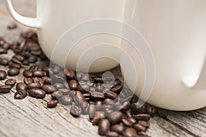 Two White Coffee Mugs Resting on Roasted Coffee Beans