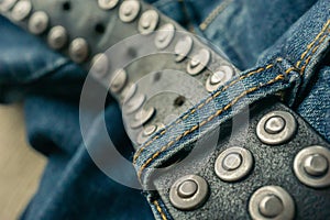 close up detail of an unbuckled leather belt on a faded pair of blue jeans