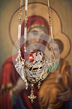 Hanging oil candle in church in front of religious iconography photo