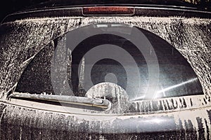 Close up detail view of lot of dust on car rear window after driving on dirt road in summer.