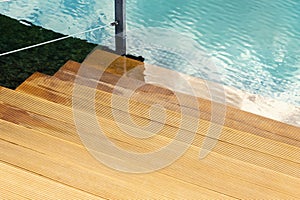 Close-up detail view of natural wooden stair steps of larch ladder into clean blue water of lake, sea or pond. Waterpoof