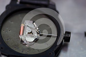 Close up of a detail of watch machinery on the table, on gray background