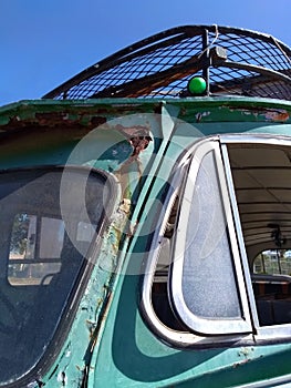 Close up detail of the windscreen and side windows of an old rusty abandoned green bus