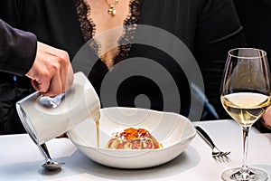 Waitress pouring seafood soup in lobster dish