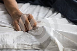 Close up detail of a womens hand grabbing on to the bed sheets, intimacy, erotic concept