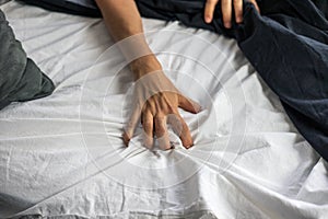 Close up detail of a womenâ€™s hand grabbing on to the bed sheets, intimacy, erotic concept