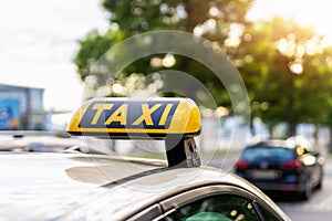 Close-up detail yellow taxi symbol on cars roof stand waiting at parking of airport terminal or railway station against