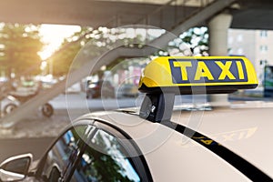 Close-up detail yellow taxi symbol on cars roof stand waiting at parking of airport terminal or railway station against