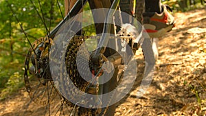 CLOSE UP: Detailed view of the rear wheel of bike as man pedals through woods