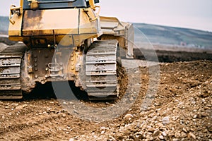 Close up details of bulldozer pushing earth and leveling ground on construction site