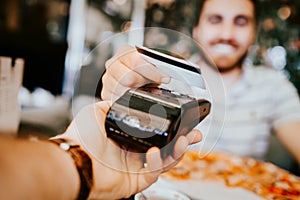 Close up details of contactless credit card payment at restaurant. Hand of customer paying with contactless credit card with