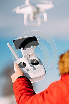 Close up details of drone remote control and white drone in blue sky. Man operating drone, pilotage details