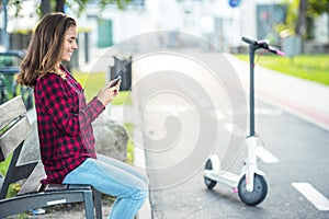 Close up details of electric scooter on the road. Ecological and urban transport in the city. Young smiling woman riding a electri