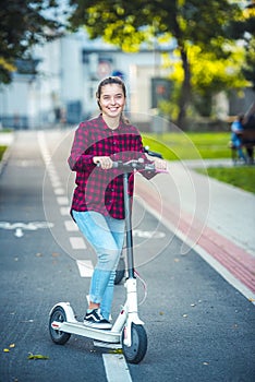 Close up details of electric scooter on the road. Ecological and urban transport in the city. Young smiling woman riding a electri