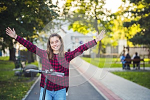 Close up details of electric scooter on the road. Ecological and urban transport in the city. Young smiling woman riding a electri