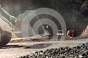 Close up details heavy construction machinery in open pit ore mine - wheel loader transports gravel at sorting plant