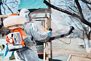 Details of man spraying disinfectant and cleaning during worldwide coronavirus pandemic. Sanitizing spaces and places photo