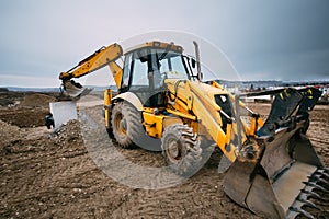 Close up details of massive working machinery, industrial backhoe loader with excavator on construction site