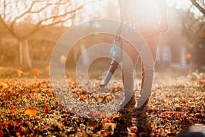 Close up details, portrait of gardener using leaf blower and vacuum. Autumn clean up