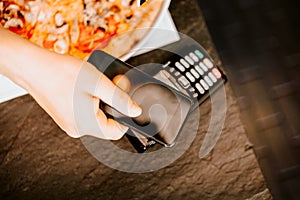 Close up details of smartphone paying at restaurant, mobile payment system