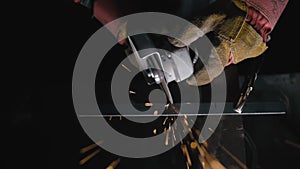 Close up details of sparks, industrial worker using angle grinder and cutting steel. Sparks fly straight in the camera