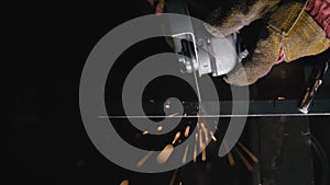 Close up details of sparks, industrial worker using angle grinder and cutting steel. Sparks fly straight in the camera