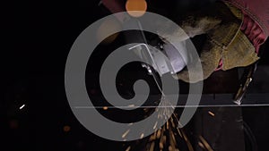 Close up details of sparks, industrial worker using angle grinder and cutting steel. Sparks fly straight in the camera