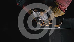 Close up details of sparks, industrial worker using angle grinder and cutting steel. Sparks fly straight in the camera