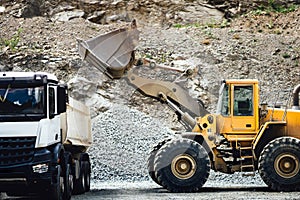 Close up details of wheel loader with scoop working on construction site and loading gravel