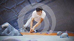 Close Up Of Determined Man Tackling Climbing Wall At Indoor Activity Centre